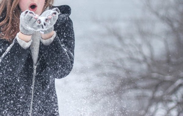 Lány fújja el a havat a kezéből